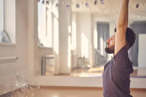 Snygg skäggig man som utövar yoga i studio — Stockfoto