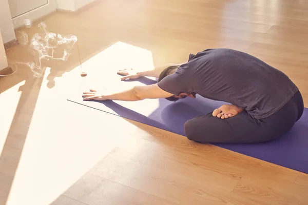 Jongeman die yoga beoefent in studio met wierookstokje op de vloer — Stockfoto