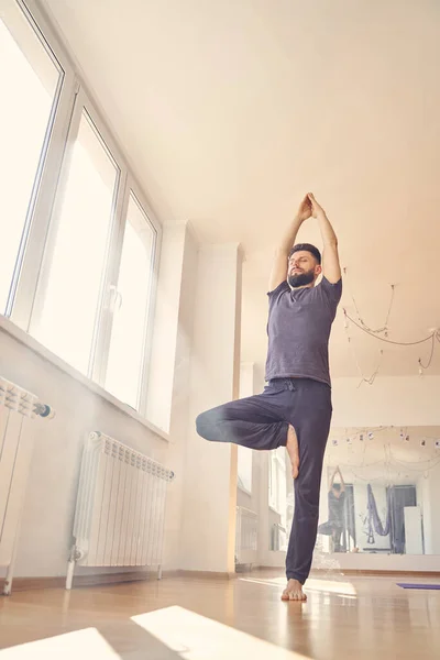 Lugn ung man gör yoga motion vid fönstret — Stockfoto