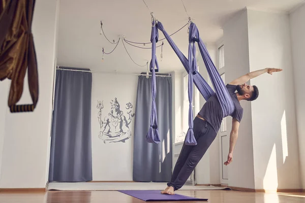 Schöner athletischer Mann praktiziert Antigravitations-Yoga im Studio — Stockfoto