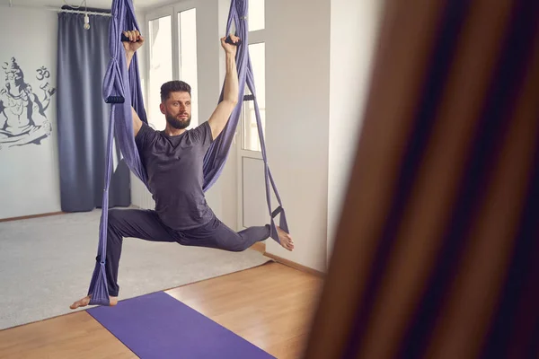 Bonito homem usando ioga balanço rede no estúdio de fitness — Fotografia de Stock