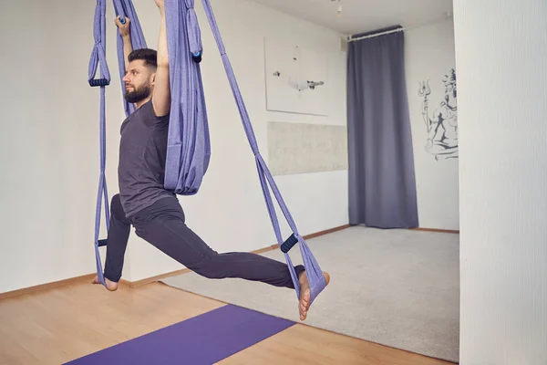 Bärtiger junger Mann nutzt blaue Hängemattenschaukel für Luft-Yoga — Stockfoto