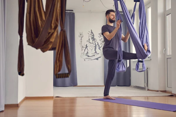 Sérieux jeune homme faisant de l'exercice de yoga aérien — Photo