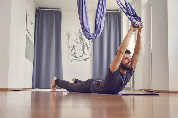 Schöner athletischer Mann praktiziert Aerial Yoga im Studio — Stockfoto