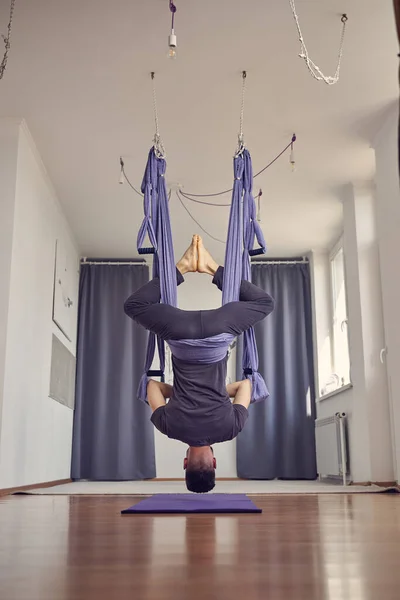Босоногий молодой человек висит вверх ногами в студии йоги — стоковое фото