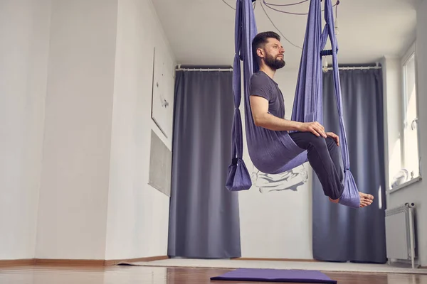 Sportlicher bärtiger Mann praktiziert Antigravitations-Yoga im Studio — Stockfoto