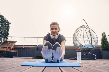 Güzel genç bir kadın terasta egzersiz yapıyor.