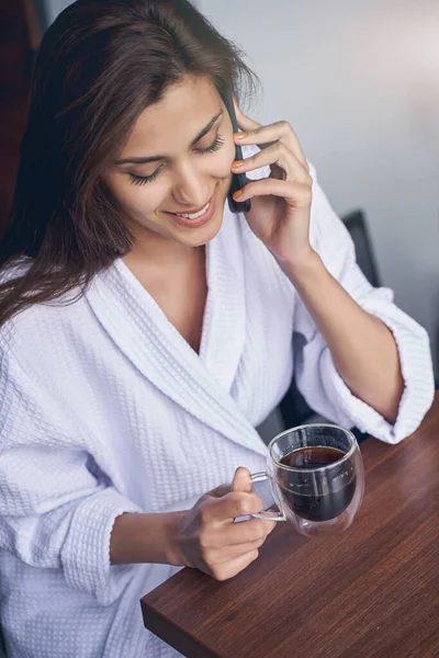 Joven alegre bebiendo café y hablando por celular —  Fotos de Stock