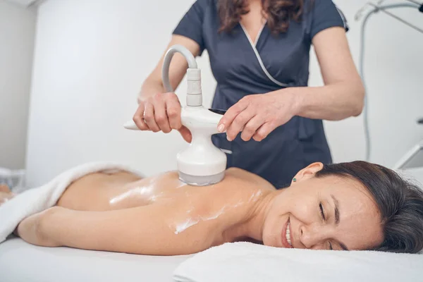 Mujer sonriente disfrutando del procedimiento de drenaje linfático en el salón de belleza — Foto de Stock