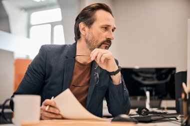 Masada elinde gözlüklerle çalışan bir erkek.