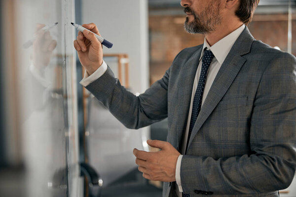 Man wearing grey suit standing near at the white board