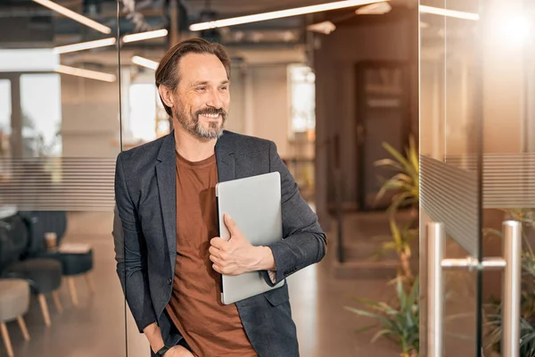 Baard zakenman met laptop staande in modern kantoor — Stockfoto