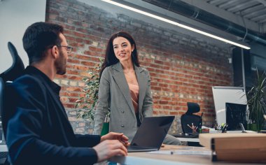 İki neşeli genç ofiste konuşuyor.