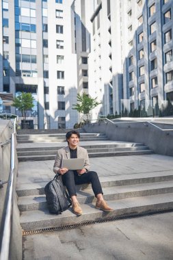 Sokakta defter kullanan neşeli genç adam.