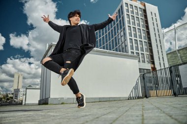 Siyah elbiseli yakışıklı adam sokaklarda numaralar yapıyor.