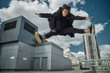 Yakışıklı genç adam sokakta zıplıyor.