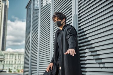 Sokakta duran koruyucu maskeli yakışıklı genç adam.
