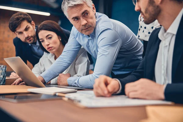 Geschäftsteam sitzt mit Laptop und Dokumenten im Büro am Tisch — Stockfoto