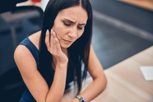 Joven bonita mujer sosteniendo mejilla y sufriendo dolor de muelas doloroso — Foto de Stock