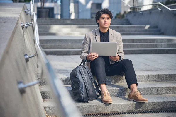 Stijlvolle jonge man met behulp van laptop op straat — Stockfoto