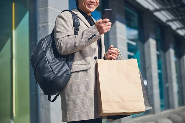 Веселий молодий чоловік використовує мобільний телефон на вулиці — стокове фото
