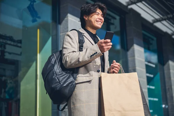 Glad ung man som använder smartphone på gatan — Stockfoto