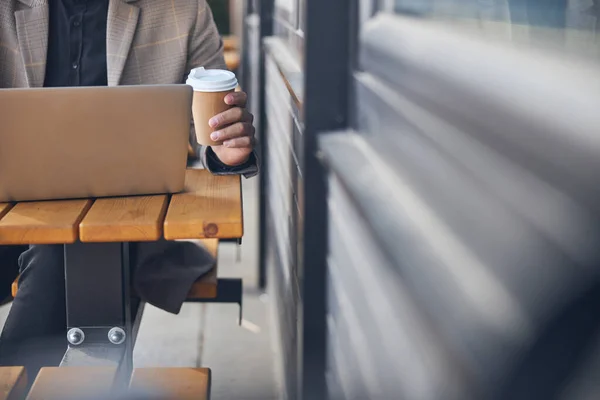 Молодий чоловік працює на ноутбуці у відкритому кафе — стокове фото