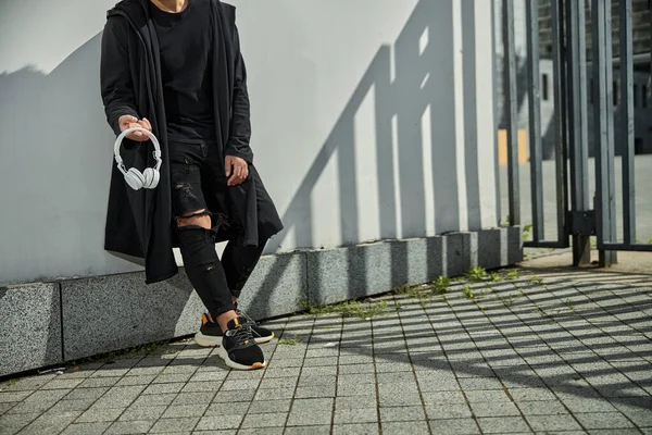 Stylish young man holding modern wireless headphones — Stock Photo, Image