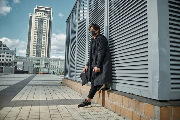 Стильный молодой человек в защитной маске стоит на улице — стоковое фото