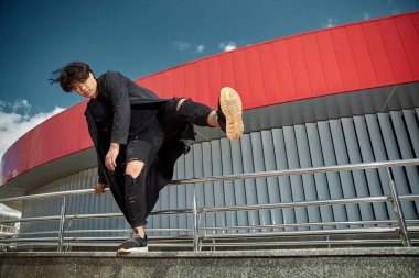 Yakışıklı genç adam sokakta bacağını kaldırıyor.