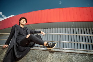 Yakışıklı genç adam sokakta dinleniyor.