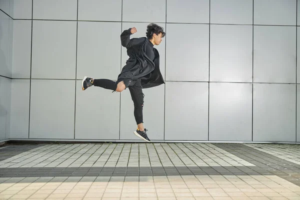 Handsome guy jumping against the wall outdoors — Stock Photo, Image