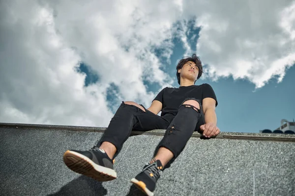 Stilig ung man sitter under vacker himmel — Stockfoto