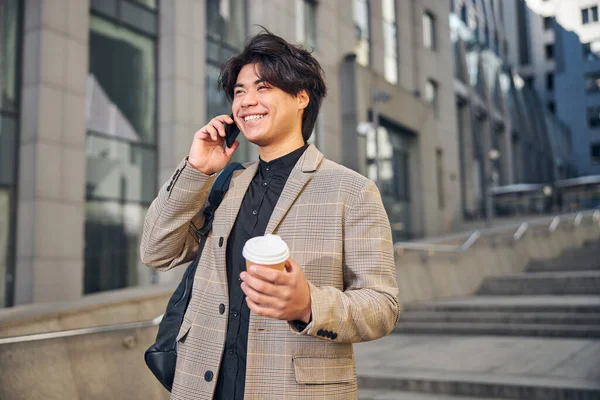 Joyeux jeune homme parlant sur son téléphone portable dans la rue — Photo