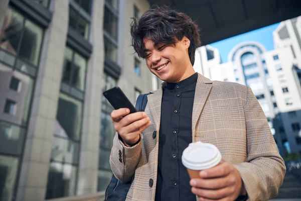 Vreugdevolle jonge man met behulp van mobiele telefoon op straat — Stockfoto