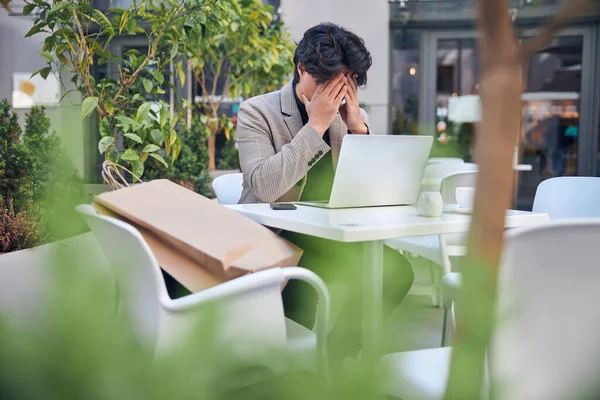 在室外咖啡店用笔记本电脑工作的疲惫不堪的年轻人 — 图库照片