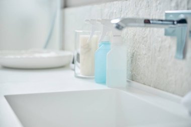 Banyo musluğu beyaz lavabonun üzerinde çeşitli spreylerle