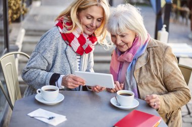 Açık hava kafesinde tablet kullanan oldukça olgun kadınlar.