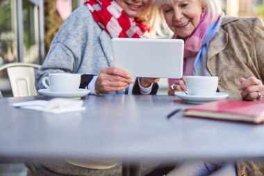 Yetişkin bir kadın arkadaşı için tablette fotoğraf gösteriyor.