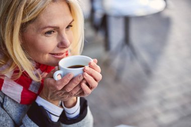 Gülümseyen mutlu kadın dışarıda kahve ile vakit geçiriyor.