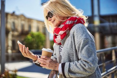 Şehirde akıllı telefon kullanan şık bir bayan.