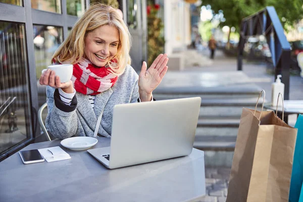 Lächelnde, fröhliche Dame mit einer Tasse Kaffee in der Hand auf der Terrasse sitzend — Stockfoto
