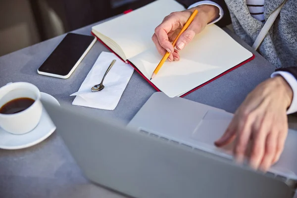 Kvinna som använder laptop i caféet medan du håller pennan — Stockfoto