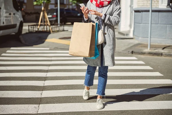 Kobieta spacerująca ulicą z papierowymi torbami na zakupy — Zdjęcie stockowe