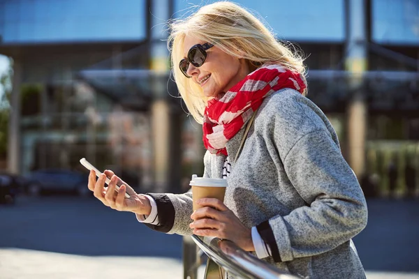 Linda loira bebendo café enquanto passeia pela cidade — Fotografia de Stock