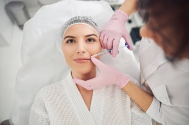 İyimser kadın hasta iğnelenebilir güzellik tedavisi görüyor.