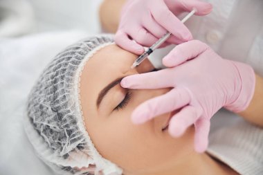 Rahatlamış genç bir kadın klinikte kaldırma prosedürü uyguluyor.