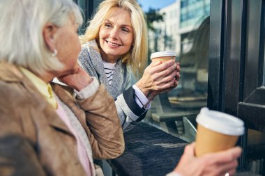 Şehir caddesinde kahveli iki neşeli kadın.