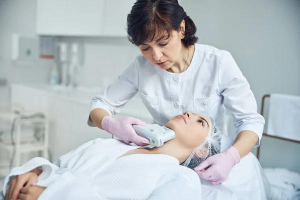 Especialista médico calificado que mejora la piel de la cara de la mujer — Foto de Stock