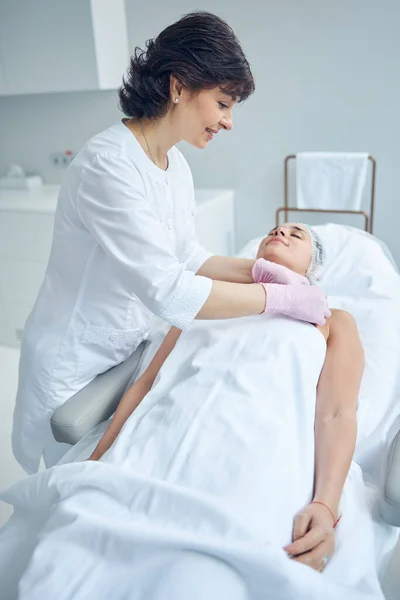 Positive beautician preparing the client for skincare treatment — Stock Photo, Image